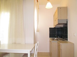 A small kitchen with a white table, a sink, and cabinets. - Irini Stalis (Hersonissos)