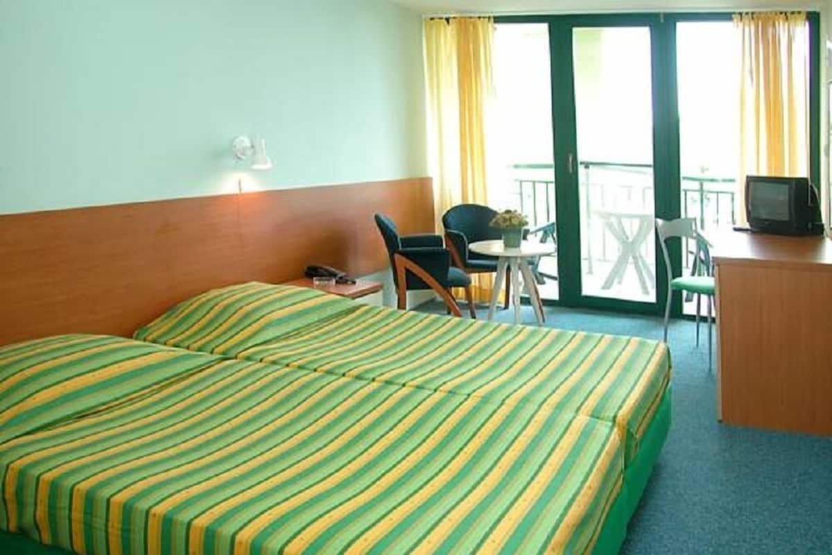 Habitación de hotel con cama doble, escritorio con televisor, silla y una mesita.
