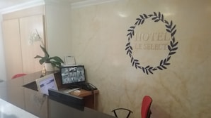 Un comptoir de réception d’hôtel avec un écran d’ordinateur, un téléphone et une photo encadrée.