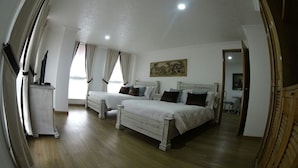 Une chambre avec deux lits, une table de chevet, une chaise et un tableau au mur.