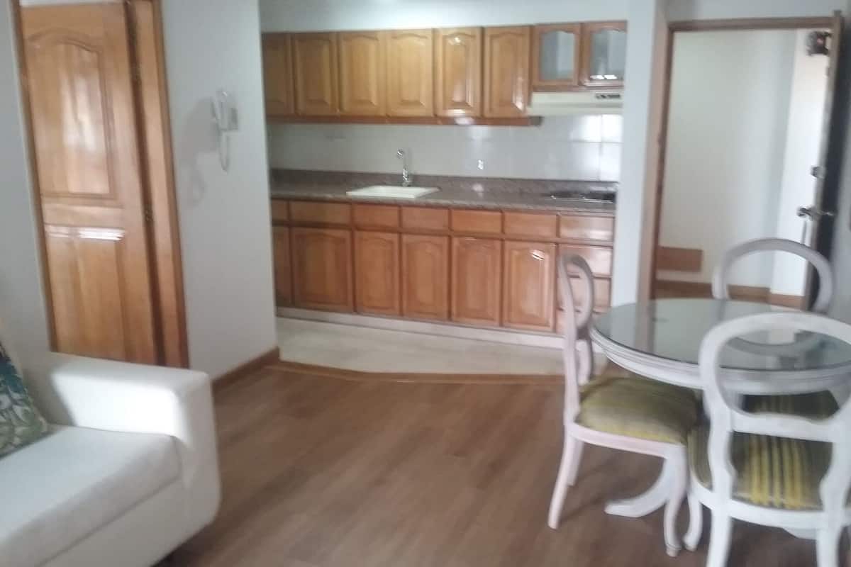 Una cocina compacta con armarios de madera, un lavabo y una zona de comedor con dos sillas.