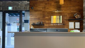 En receptionsdisk med en trævæg, et Samsung- og et LG-køleskab, samt et skilt der angiver, at det er et hostel og resort.