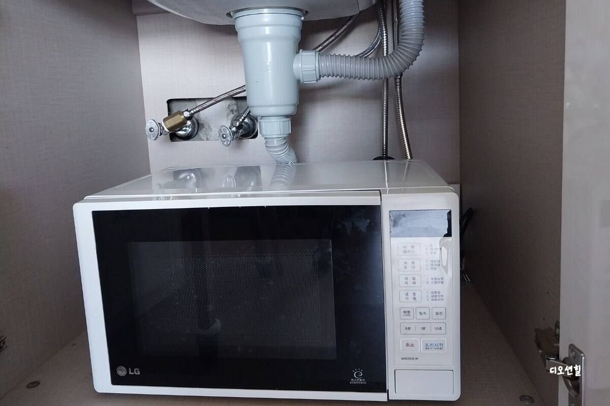 Un four à micro-ondes doté d’un distributeur d’eau fixé au mur, juste au-dessus.