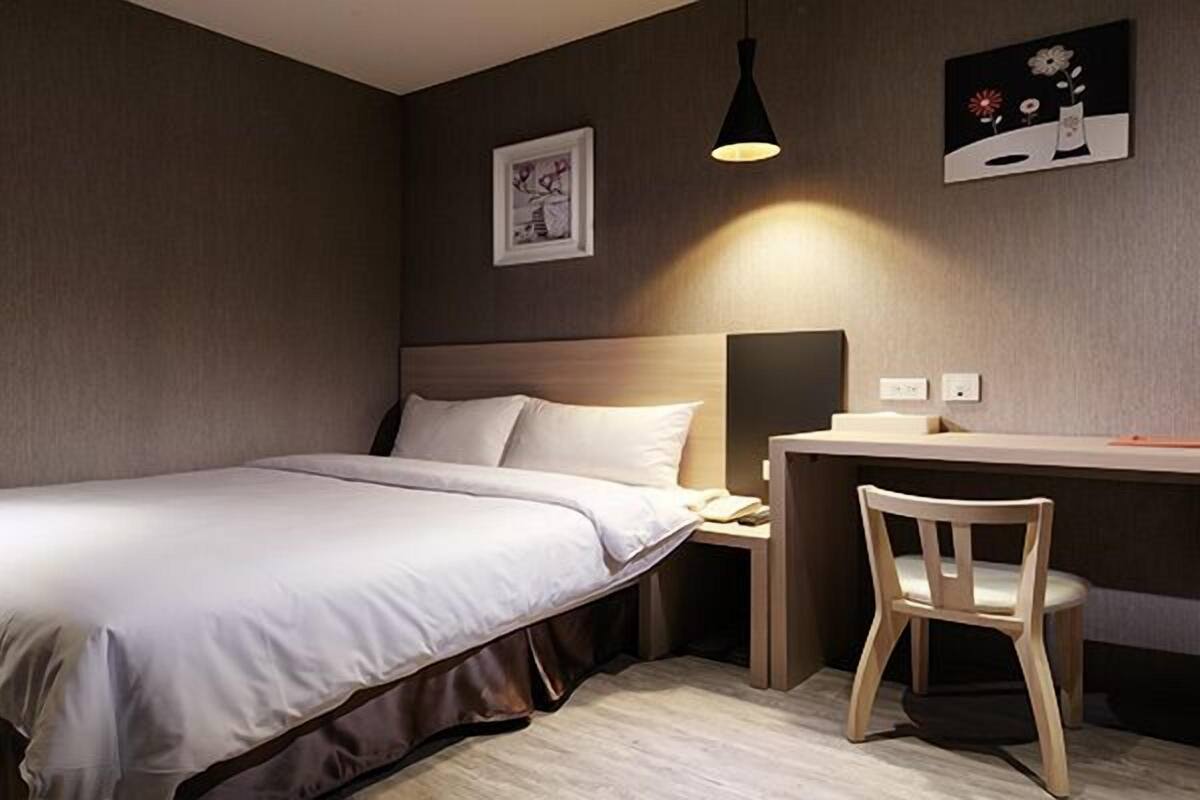 Une chambre d’hôtel bien rangée, avec un lit, un bureau et une chaise.