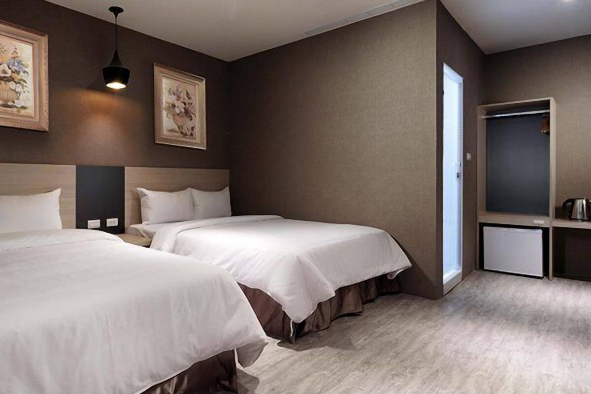 Une chambre d’hôtel avec deux lits, une petite kitchenette et des œuvres d’art accrochées aux murs.