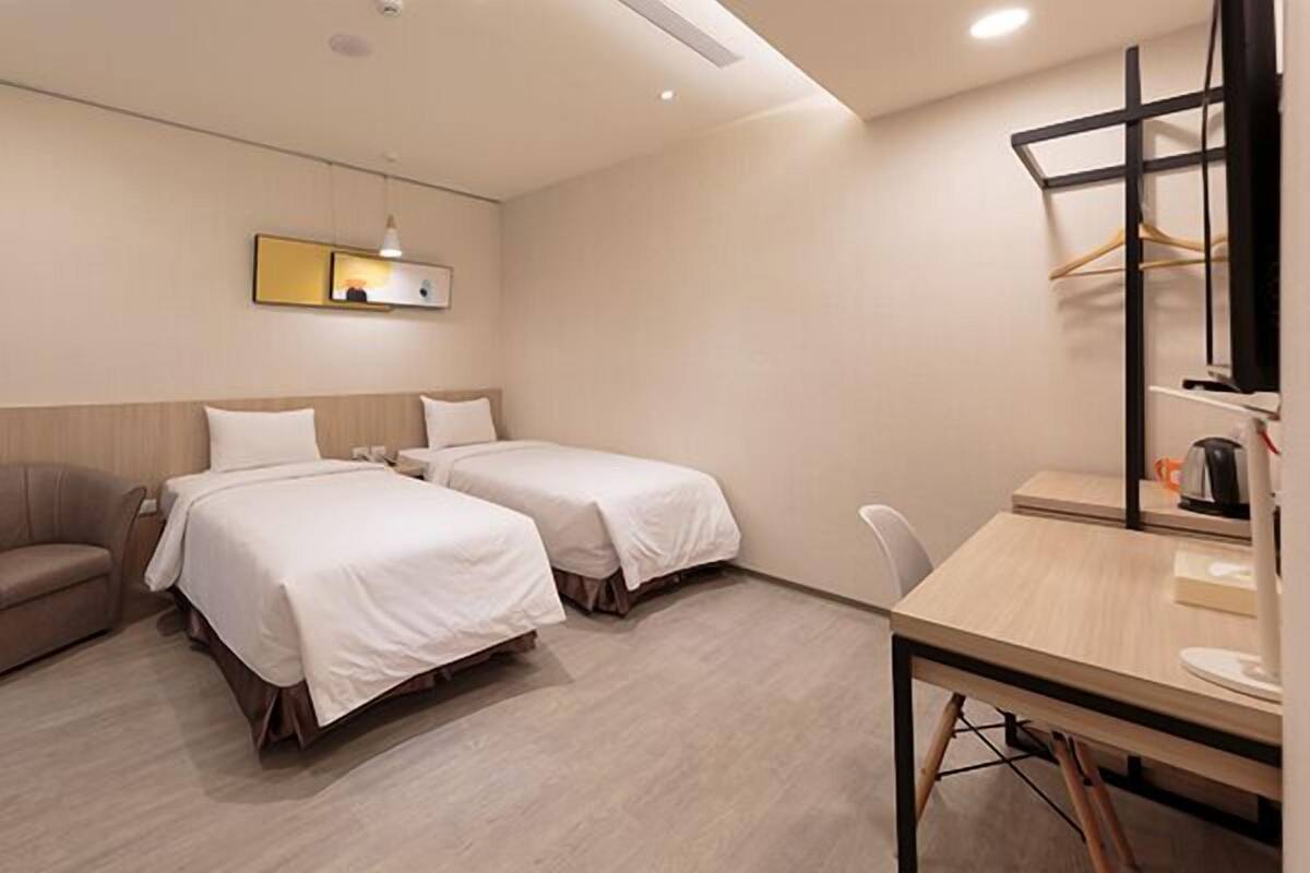 Une chambre d’hôtel avec deux lits, un canapé, un bureau et une petite table.