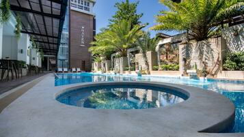 Una piscina al aire libre, sillones reclinables de piscina