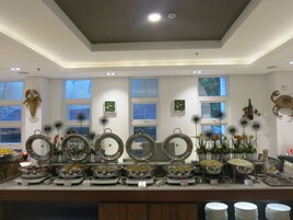 Uma área de buffet com vários pontos de serviço de comida, obras de arte decorativas na parede e teto com iluminação embutida.