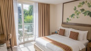 Une chambre d’hôtel avec un grand lit, une vue sur la verdure par la fenêtre et un balcon aménagé avec du mobilier d’extérieur.