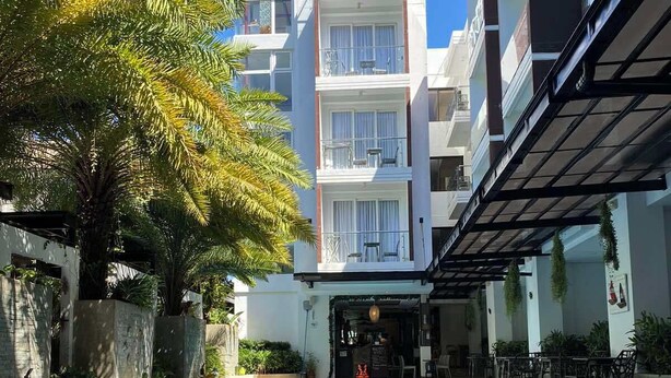 Une piscine de forme circulaire, entourée d’un bâtiment doté de balcons et d’un espace de détente extérieur.