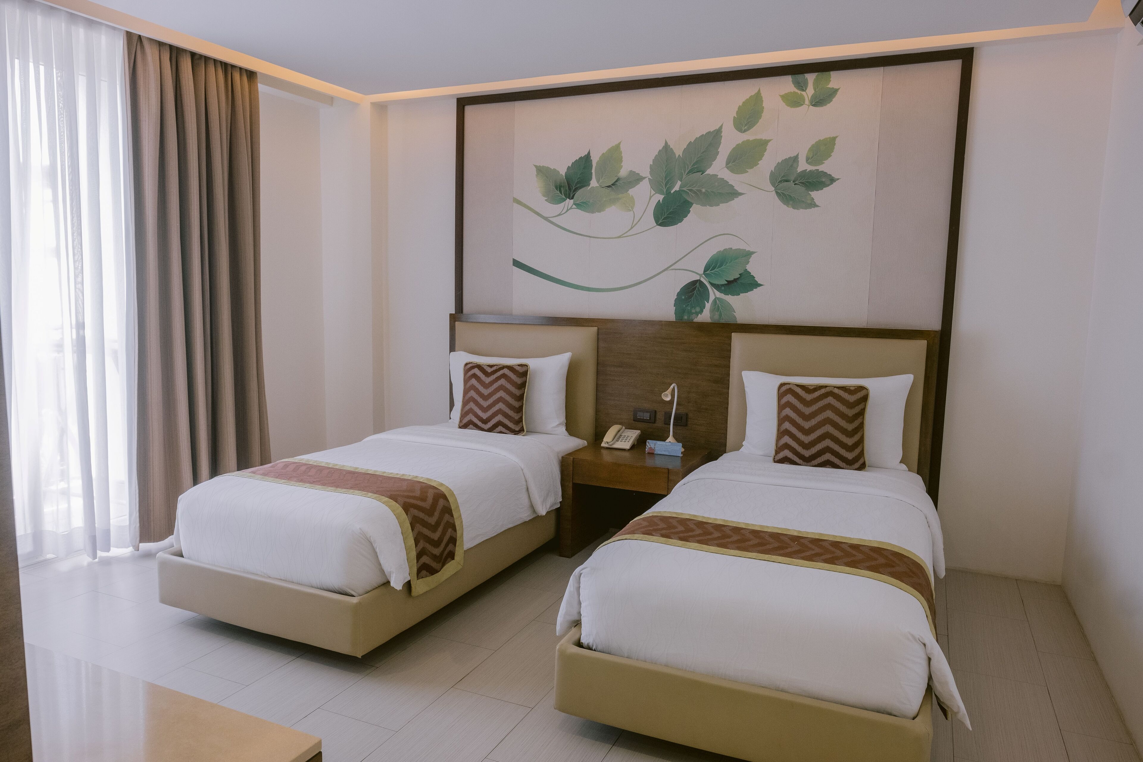 Habitación de hotel con dos camas, una mesita de noche, un teléfono y una obra de arte colgada en la pared.