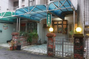 A traditional Japanese house with a covered entrance, a brick gate, and potted plants.