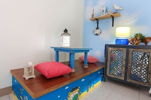 Een kamer met een houten bureau, een blauwe tafel, een kast met decoratieve panelen en een wandplank met spullen.