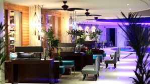 Een moderne lobby met een receptiebalie, zithoek en een zwembad.