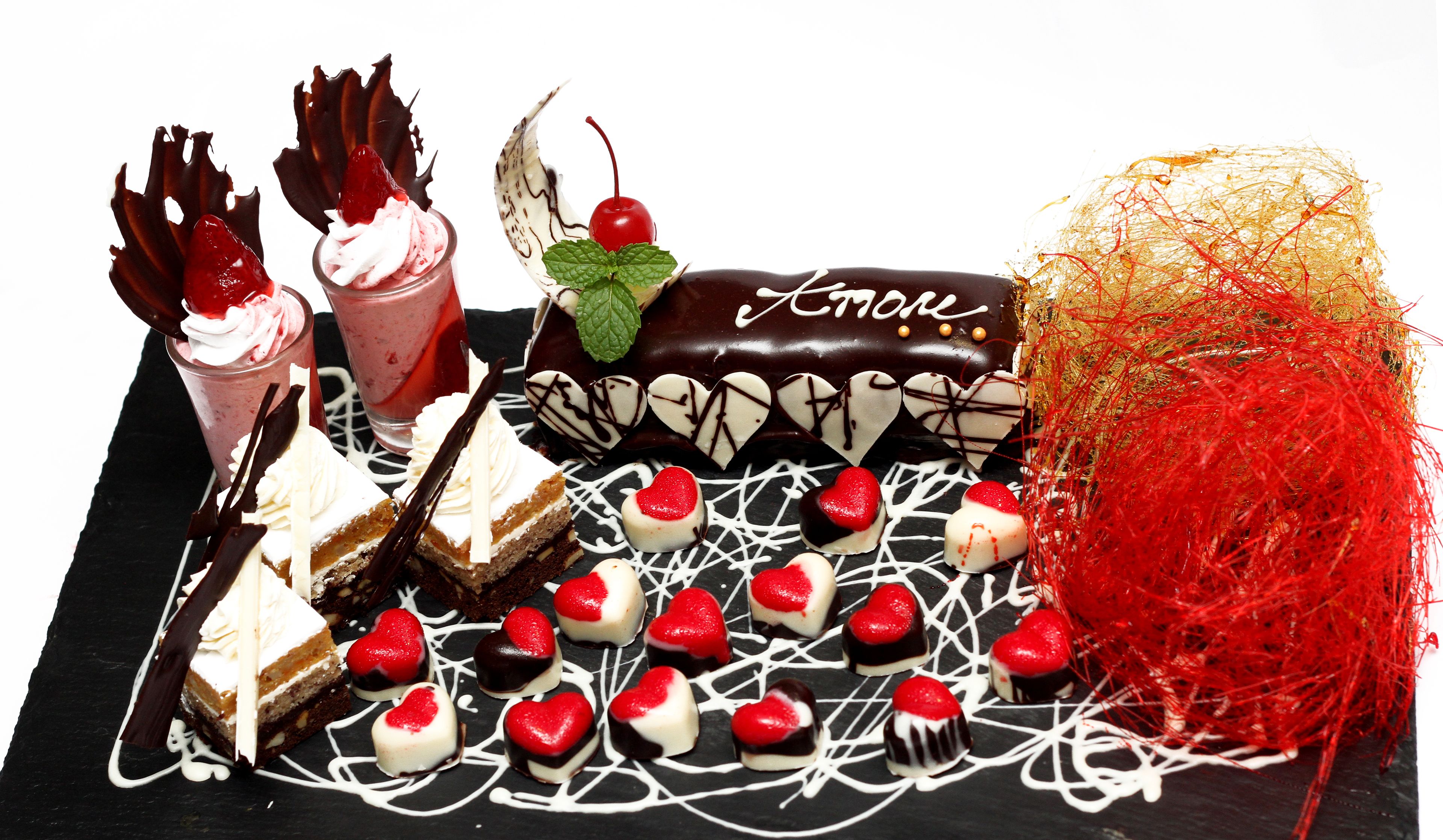 Une variété de desserts, notamment des gâteaux, des glaces et des fraises enrobées de chocolat, disposés sur une surface en ardoise noire.