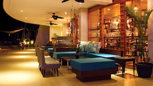 Een moderne lounge met zitplaatsen, plafondventilatoren en een bar met flessen.