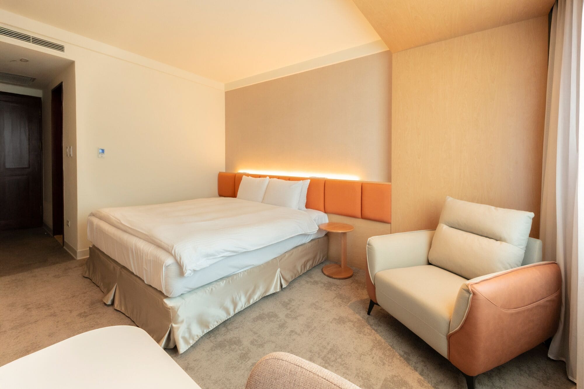 A hotel room with a bed, a chair, and a small table.
