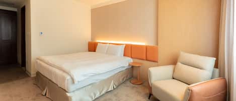 Una habitación de hotel con una cama, una silla y una mesita.