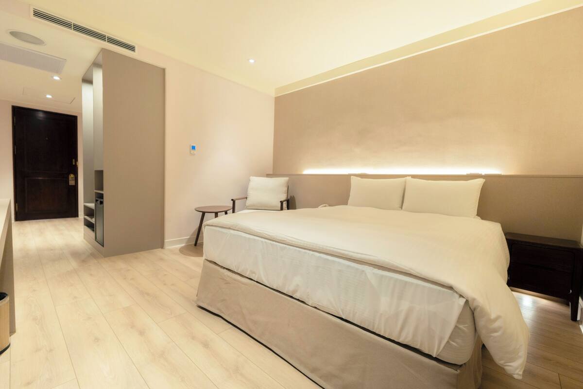 Ein modernes Hotelzimmer mit einem großen Bett, Nachttischen und einem Einbauschrank.