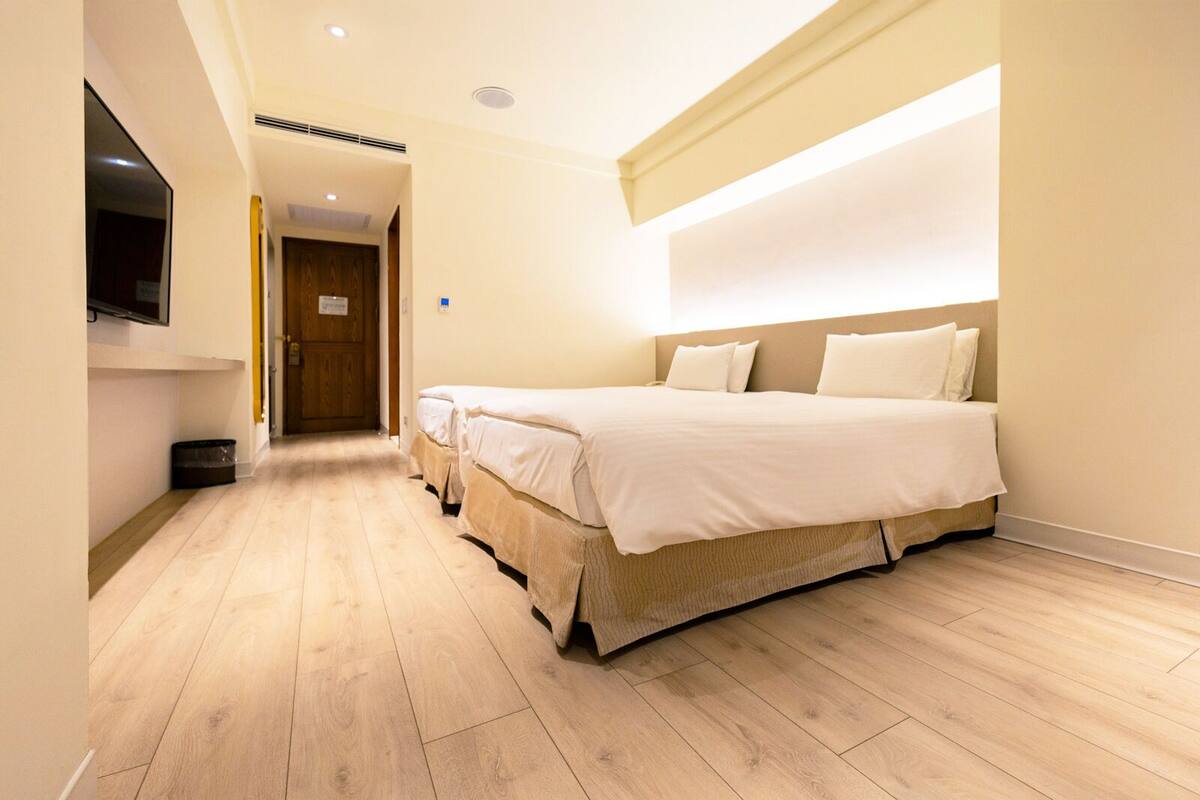 Ein Hotelzimmer mit einem großen Bett, einem an der Wand montierten Fernseher und Holzboden.