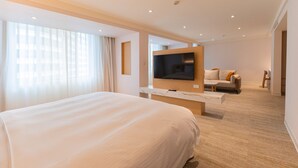 A modern hotel room with a large bed, a flat-screen TV mounted on the wall, a sofa, and a small table. - Hotel Tainan (Tainan)