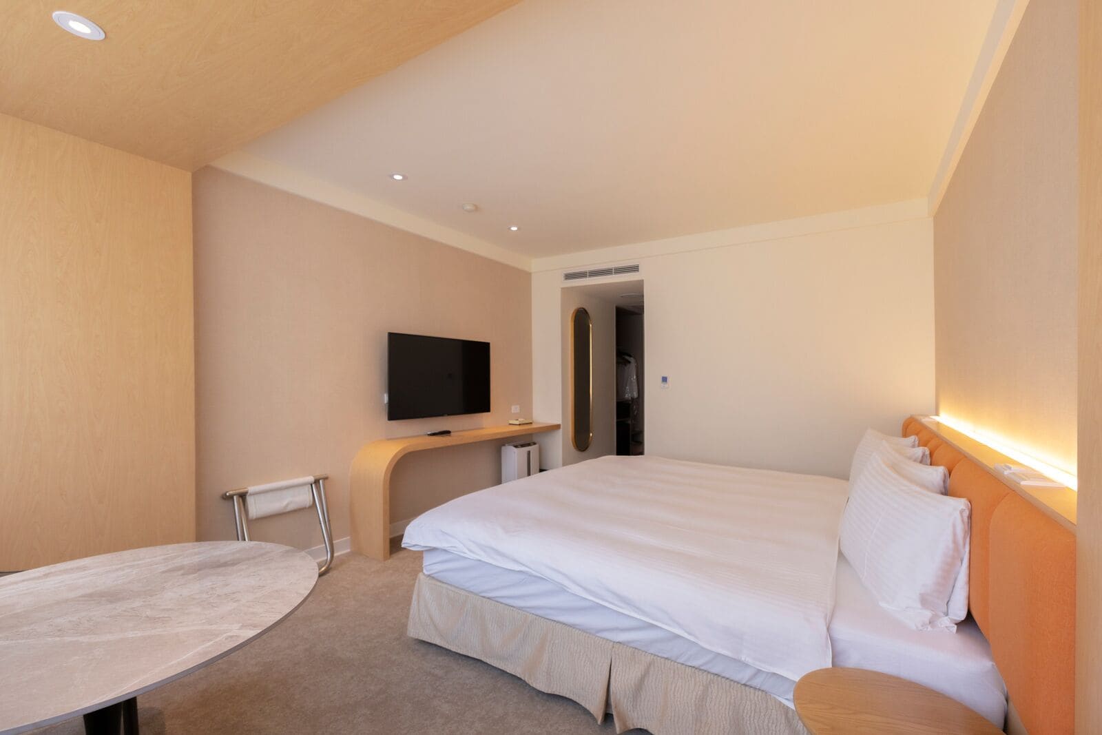 Une chambre d’hôtel avec un lit, un téléviseur fixé au mur, un bureau et une chaise.