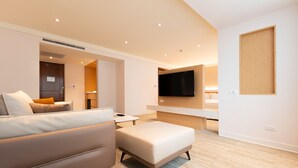 A modern hotel room with a sofa, ottoman, flat-screen TV, and a small table. - Hotel Tainan (Tainan)