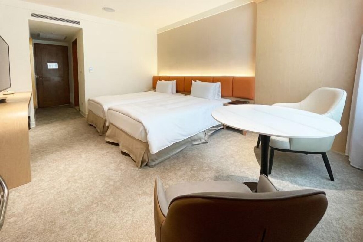 A hotel room with a bed, a round table, a chair, and a television.