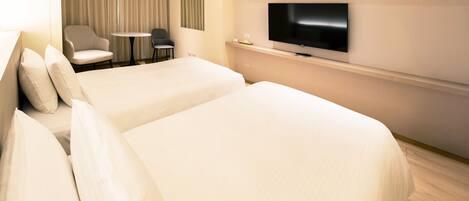 A hotel room with two beds, a TV, a small table, and a chair.
