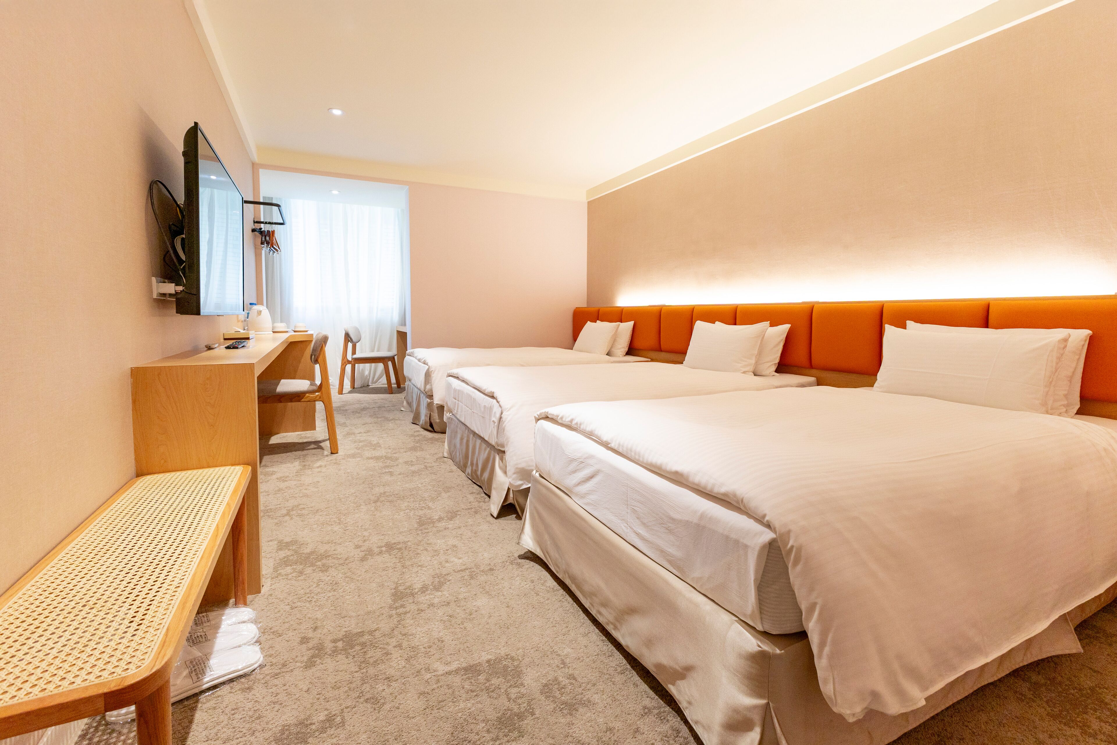 Una habitación de hotel con dos camas, un escritorio, una silla y un banco.