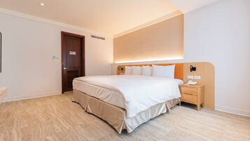 Een moderne hotelkamer met een groot bed, een nachtkastje en een vastgezet hoofdbord.
