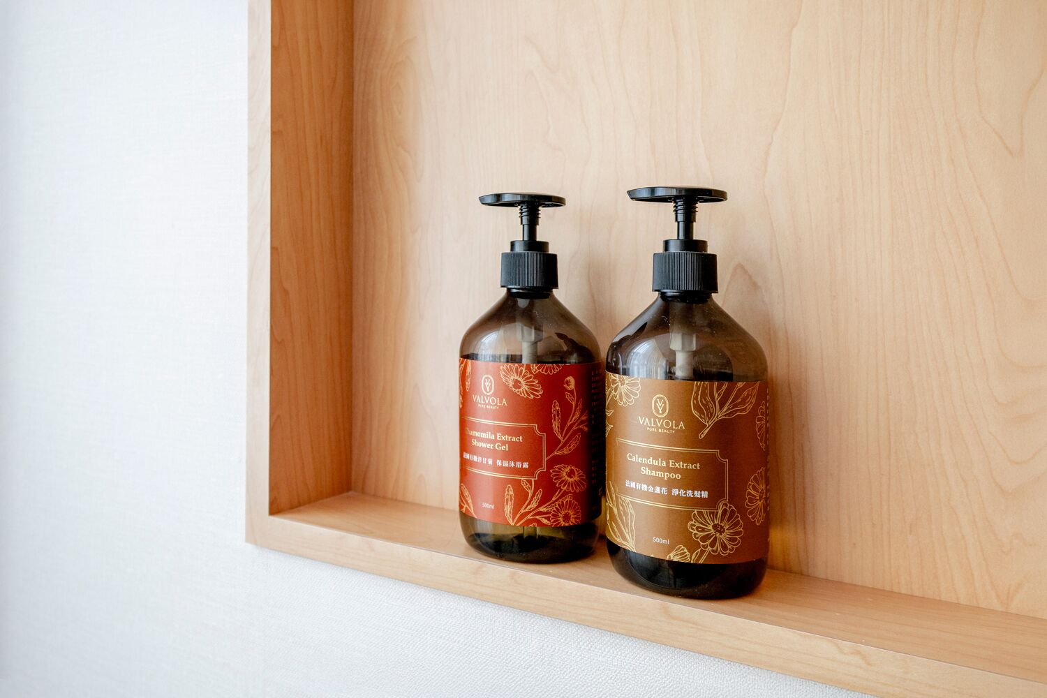 Two bottles of Valvola shampoo on a wooden shelf.
