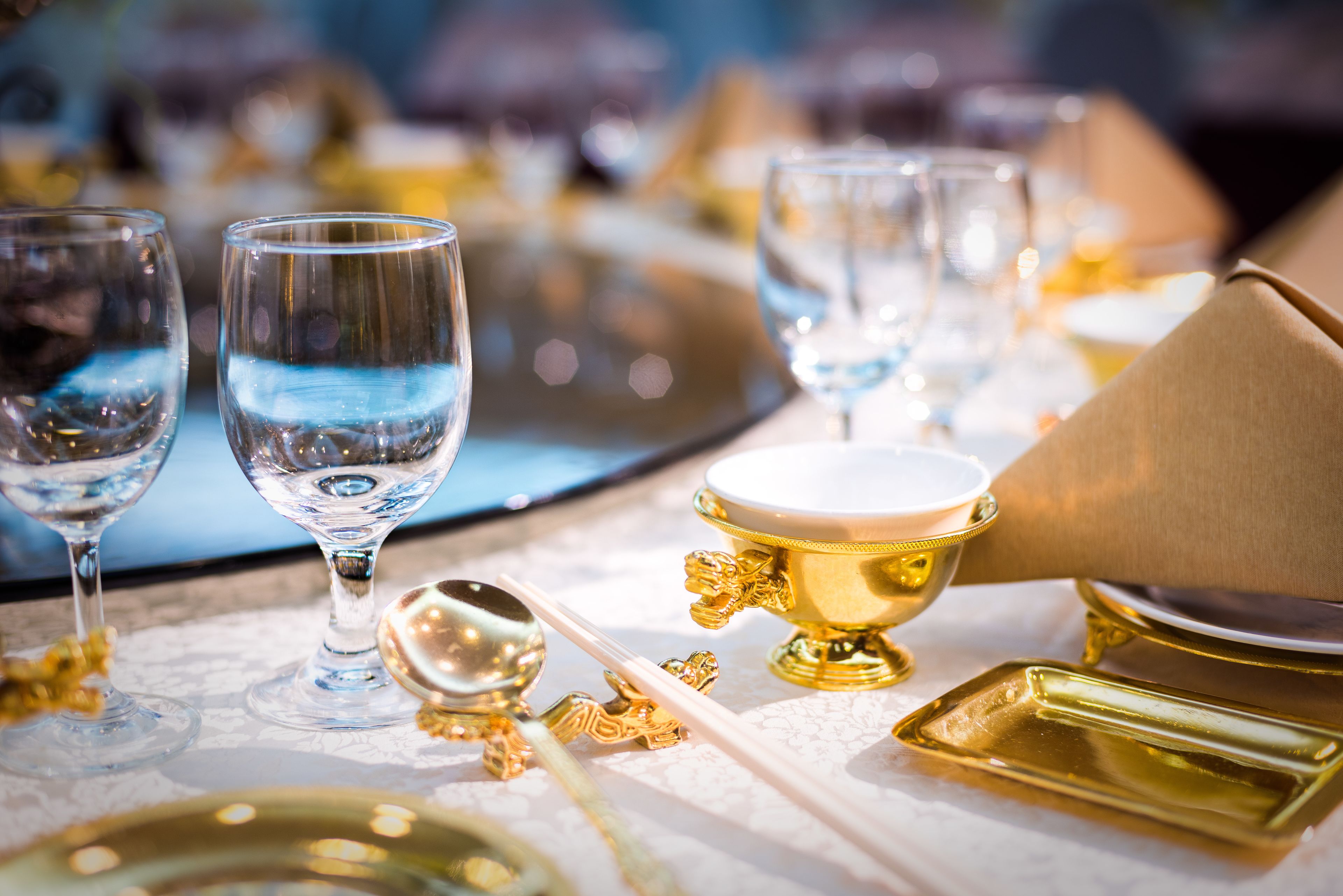 A table set with gold and white tableware, including glasses, a spoon, and a gold bowl.