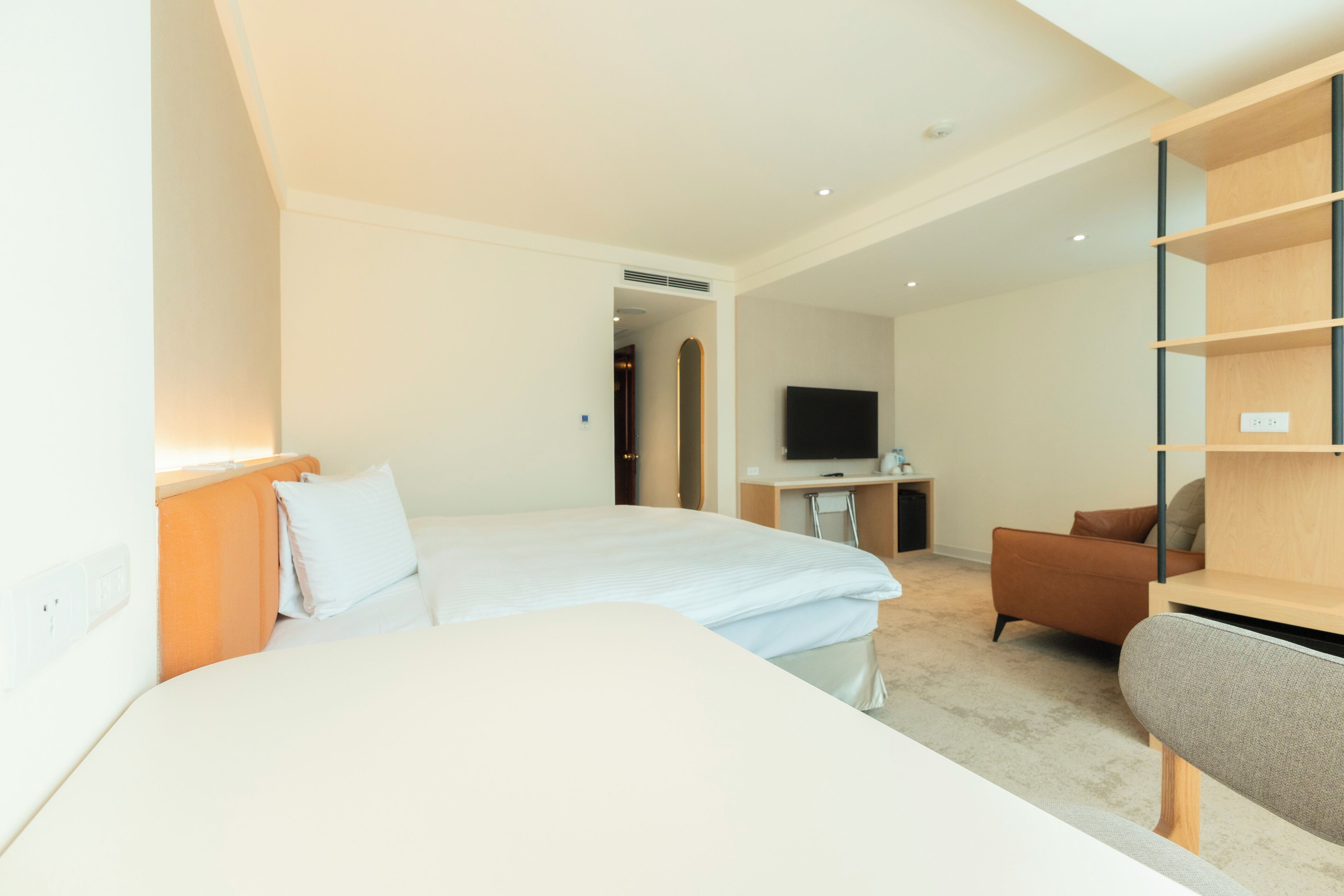 Une chambre d’hôtel avec un grand lit, un bureau avec une chaise, une télévision et une armoire.