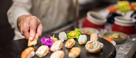 A sushi platter with various types of sushi and a hand picking one.