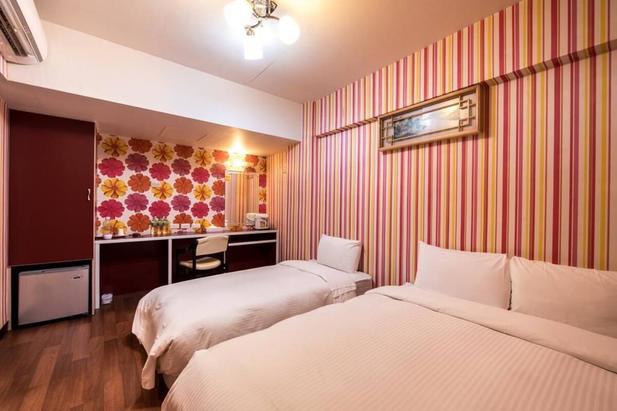 A hotel room with two beds, a desk, and a chair.