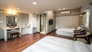A hotel room with two beds, a desk with a mirror, a small stool, and a TV.