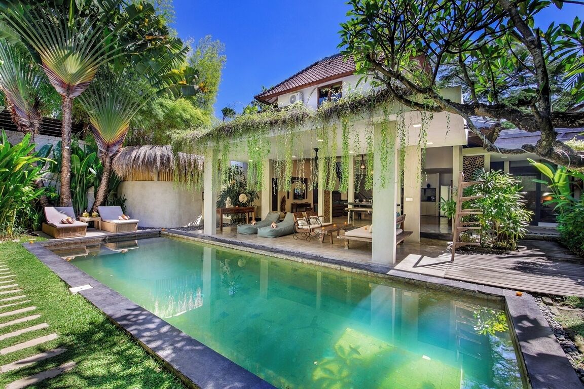 A swimming pool with lounge chairs and a covered seating area.