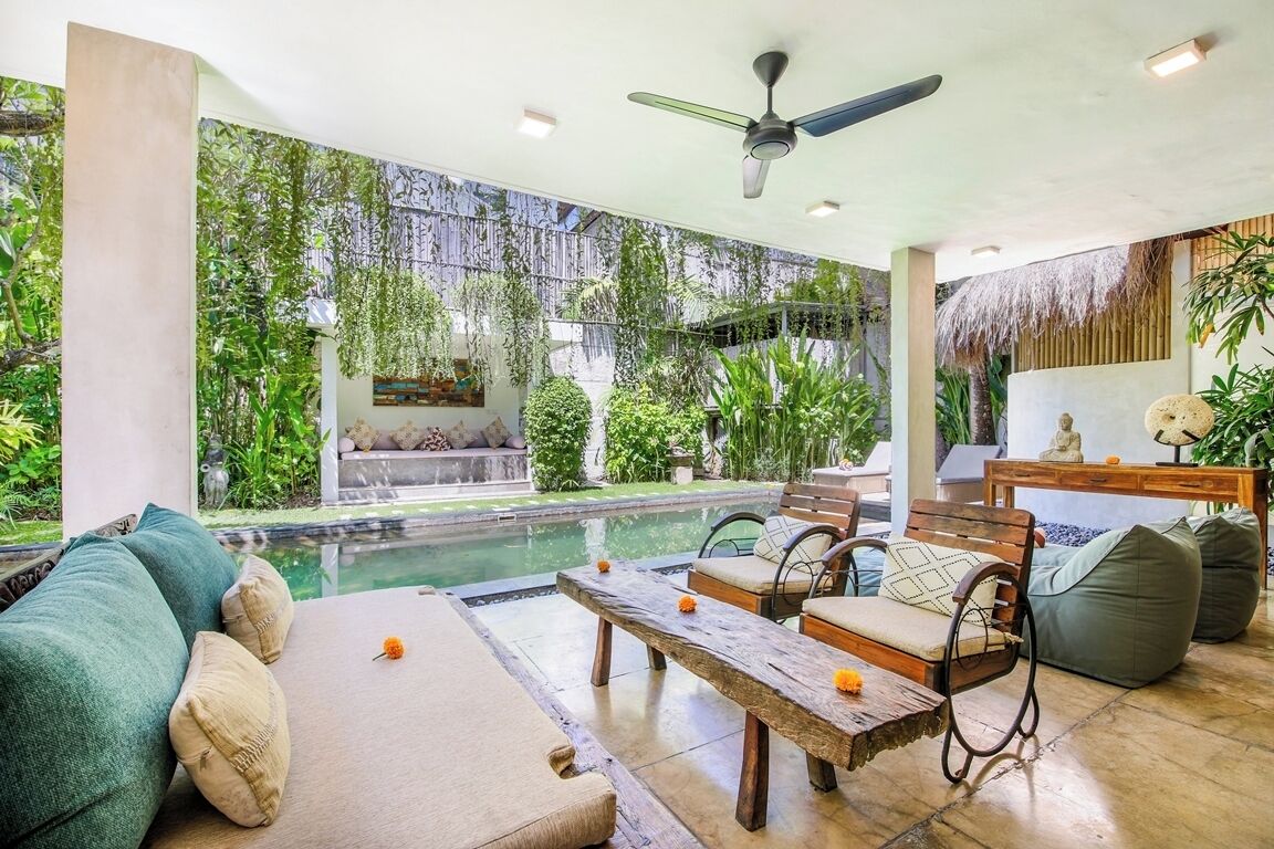 Zona de piscina con sofá, sillas y una mesa.