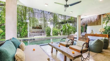 Zona de piscina con sofá, sillas y una mesa.