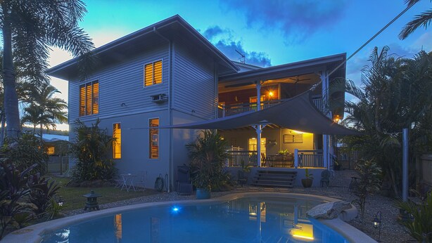 Ein zweistöckiges Haus mit Swimmingpool, überdachter Terrasse und gepflegtem Garten.