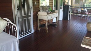 Eine hölzerne Veranda mit einem weißen Tisch, einer weißen Bank und einer Tür mit Glasfenster.