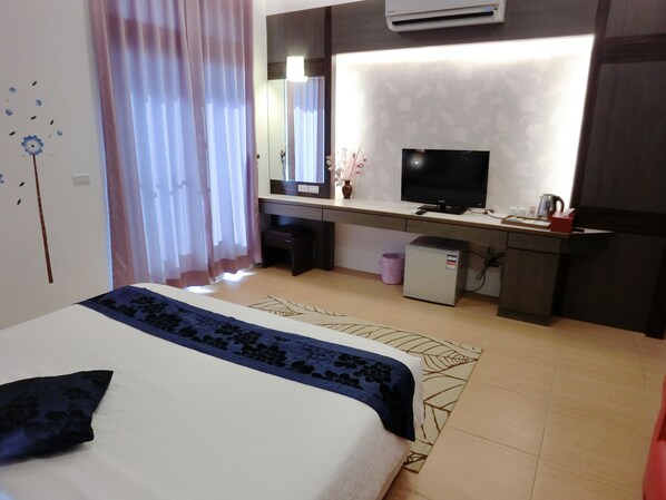 A hotel room with a bed, a desk, a television, and a small refrigerator.