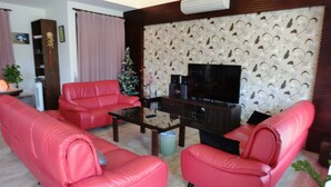 A living room with a red sofa set, a coffee table, and a TV on a patterned wall. - Love Play House (Luodong)
