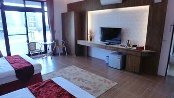 Ein Hotelzimmer mit Bett, Schreibtisch, Fernseher, kleinem Kühlschrank und Stuhl.