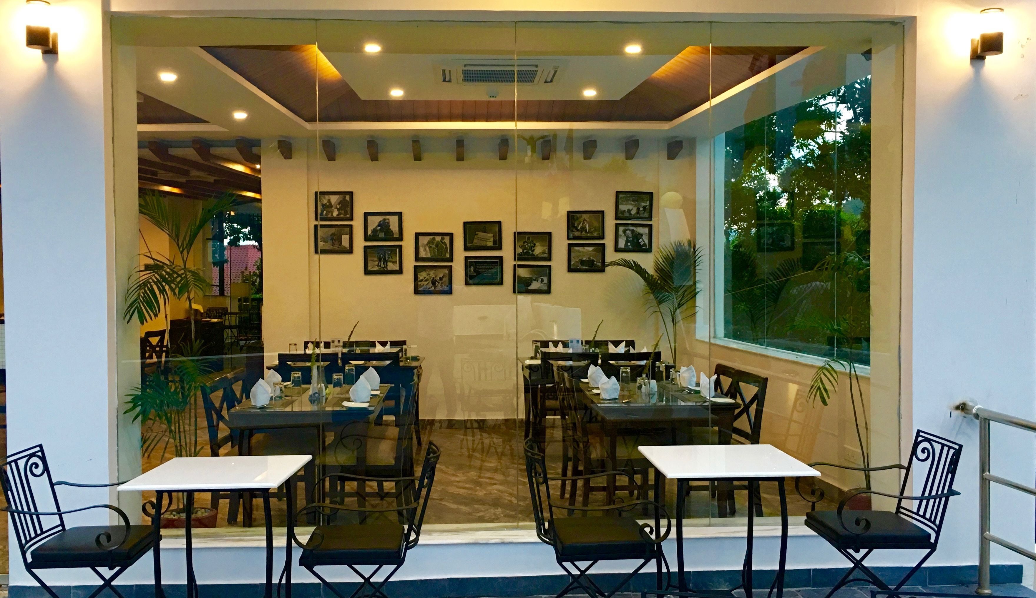 Un restaurant avec des tables et des chaises, des tableaux encadrés accrochés au mur et une grande fenêtre.