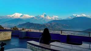 A person standing on a balcony overlooking snow-capped mountains. - Himalayan Front Hotel by KGH Group (Pokhara)