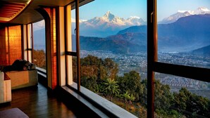 A modern interior with large windows offering a view of a mountainous landscape and a city below. - Himalayan Front Hotel by KGH Group (Pokhara)