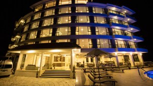 A multi-story hotel with a curved facade, outdoor seating area, and a visible entrance with steps leading up to the door. - Himalayan Front Hotel by KGH Group (Pokhara)