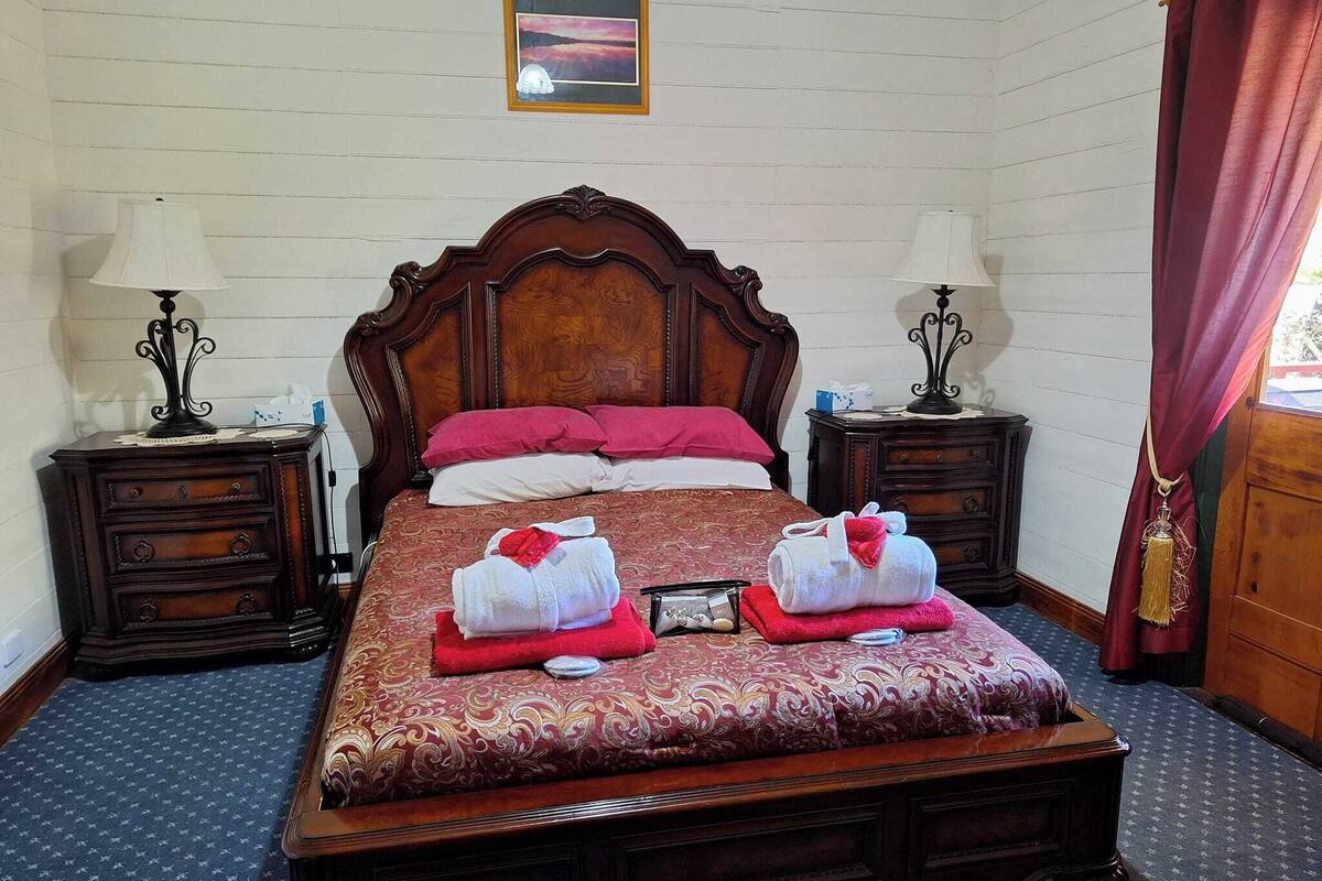 A neatly made bed with a wooden headboard, two bedside tables with lamps, and a picture on the wall.